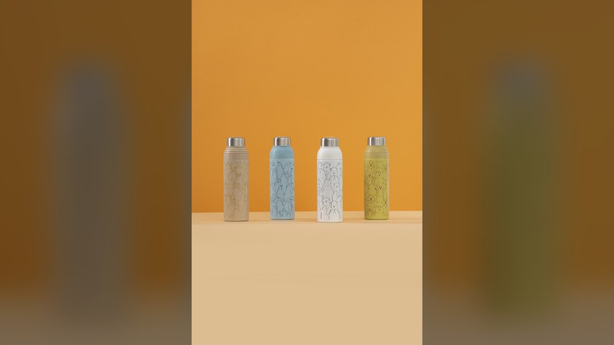 Four pastel tumblers lined up against a warm orange wall