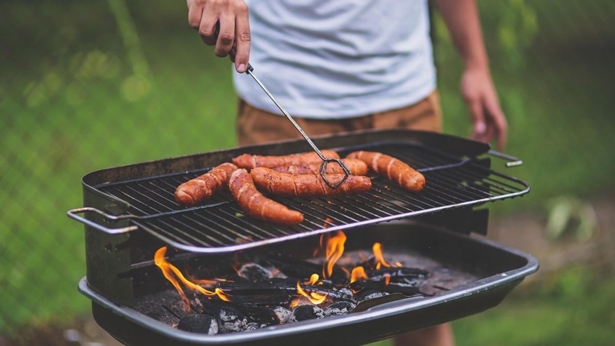 Sausages cooking over a charcoal grill in a backyard