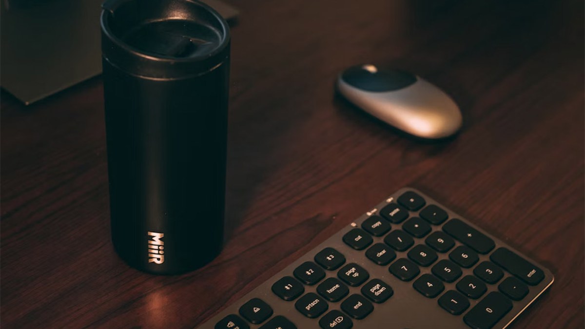 Black insulated tumbler on a desk beside a keyboard and mouse